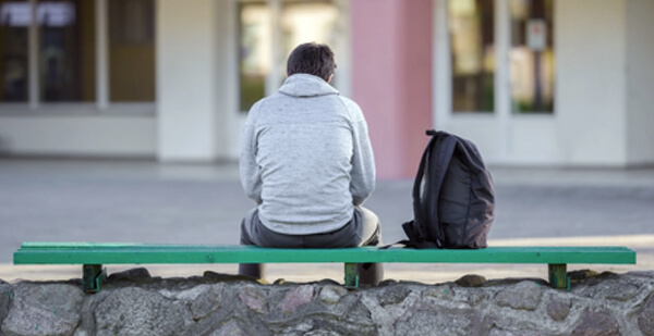 Photo of man sitting on bench with backpack